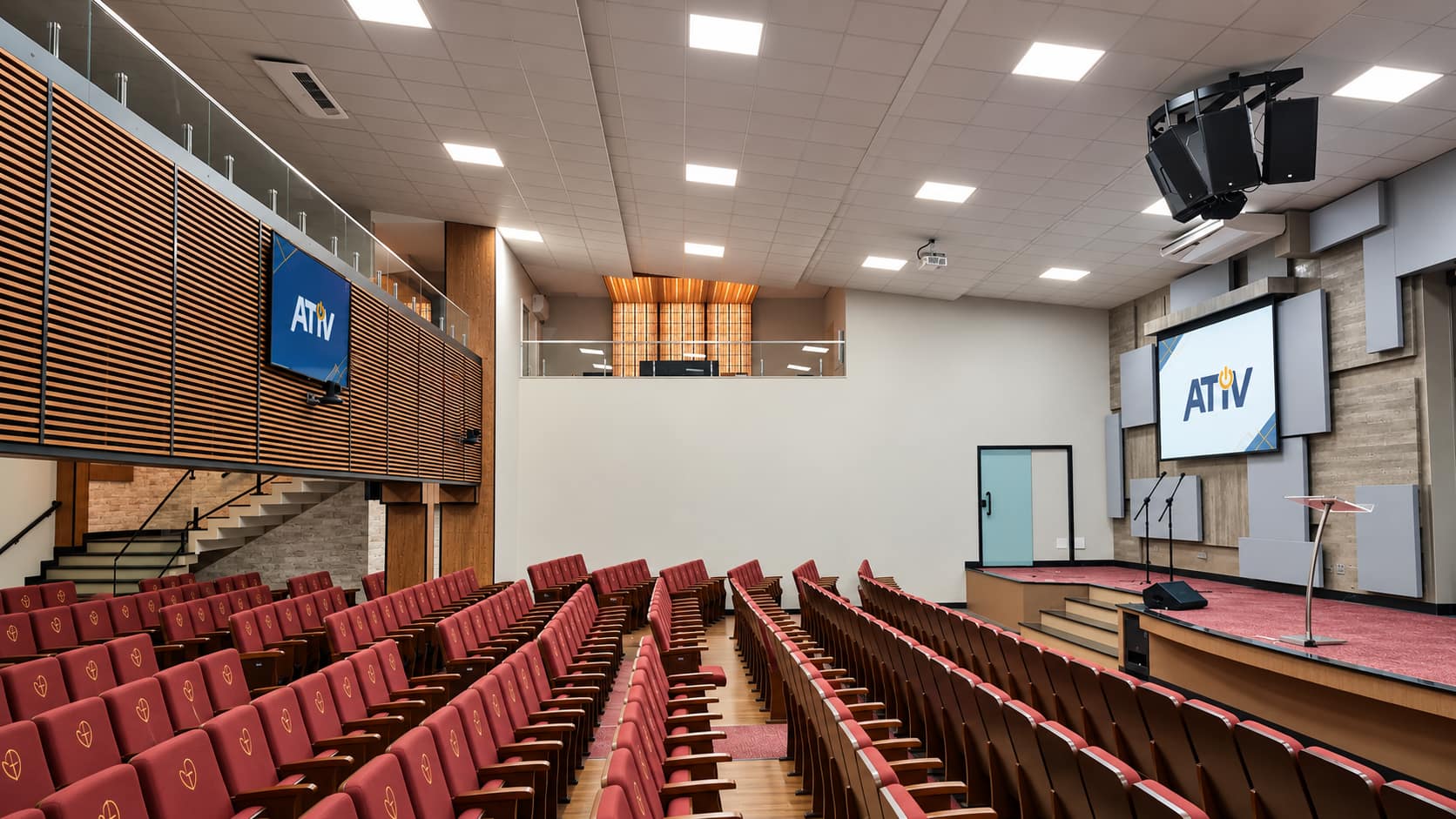 Auditório com assentos vermelhos e palco