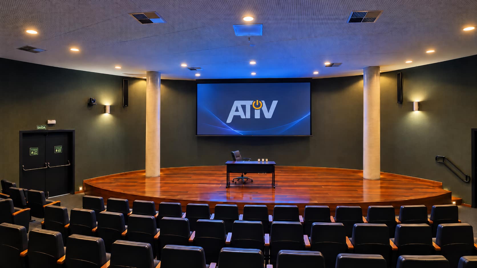 Auditório do TCM SP com plateia, palco e tela de projeção